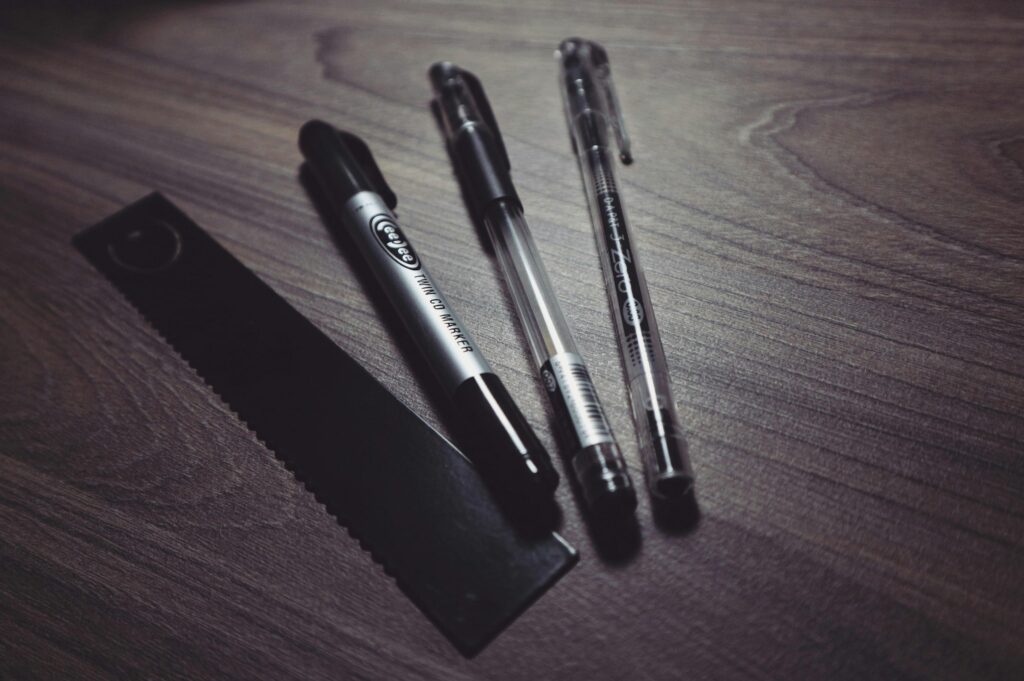 A close-up of pens and a ruler on a dark wooden desk surface, perfect for office themes.